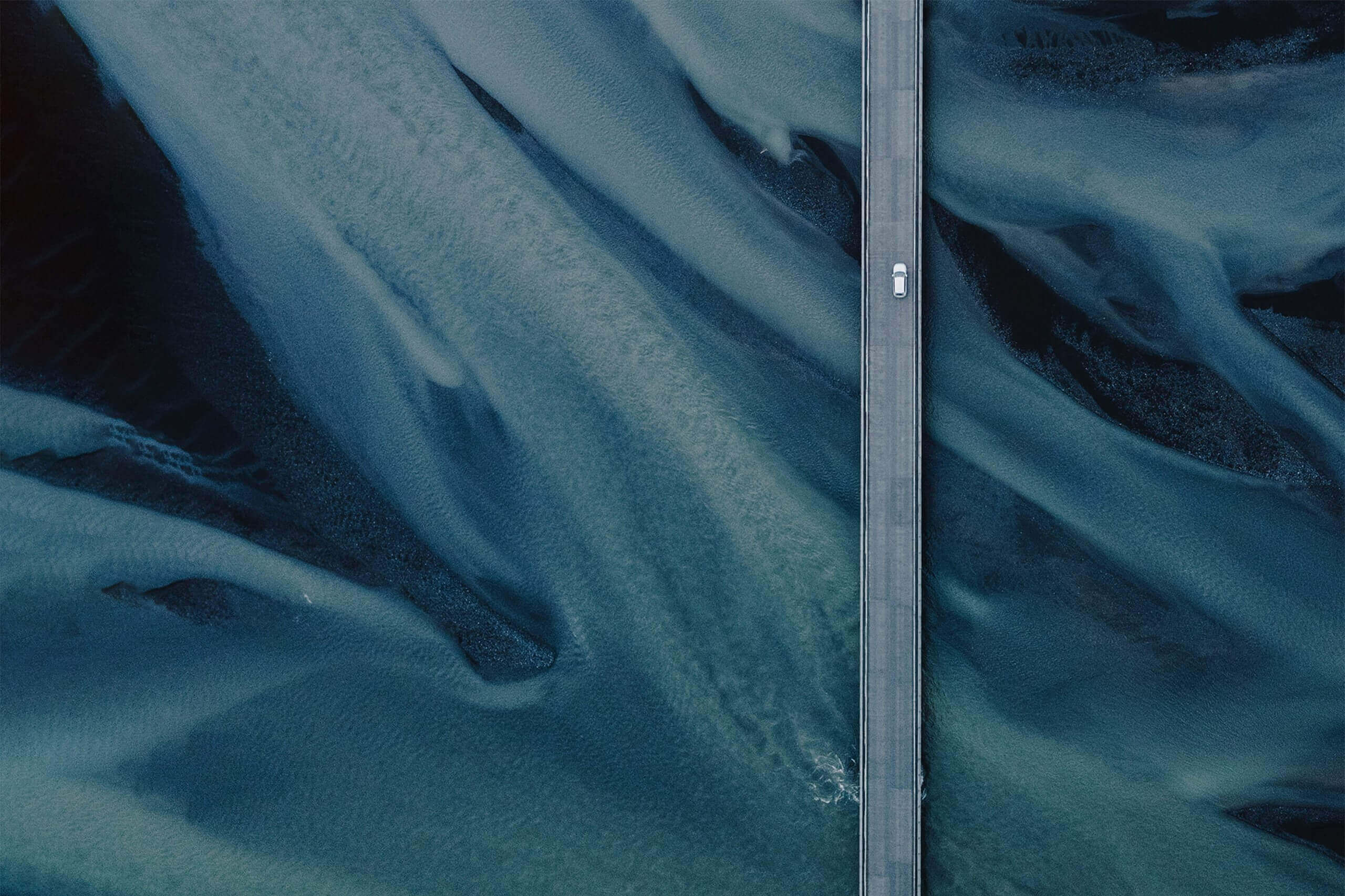 Photographie aérienne d'une voiture sur une route qui traverse le désert